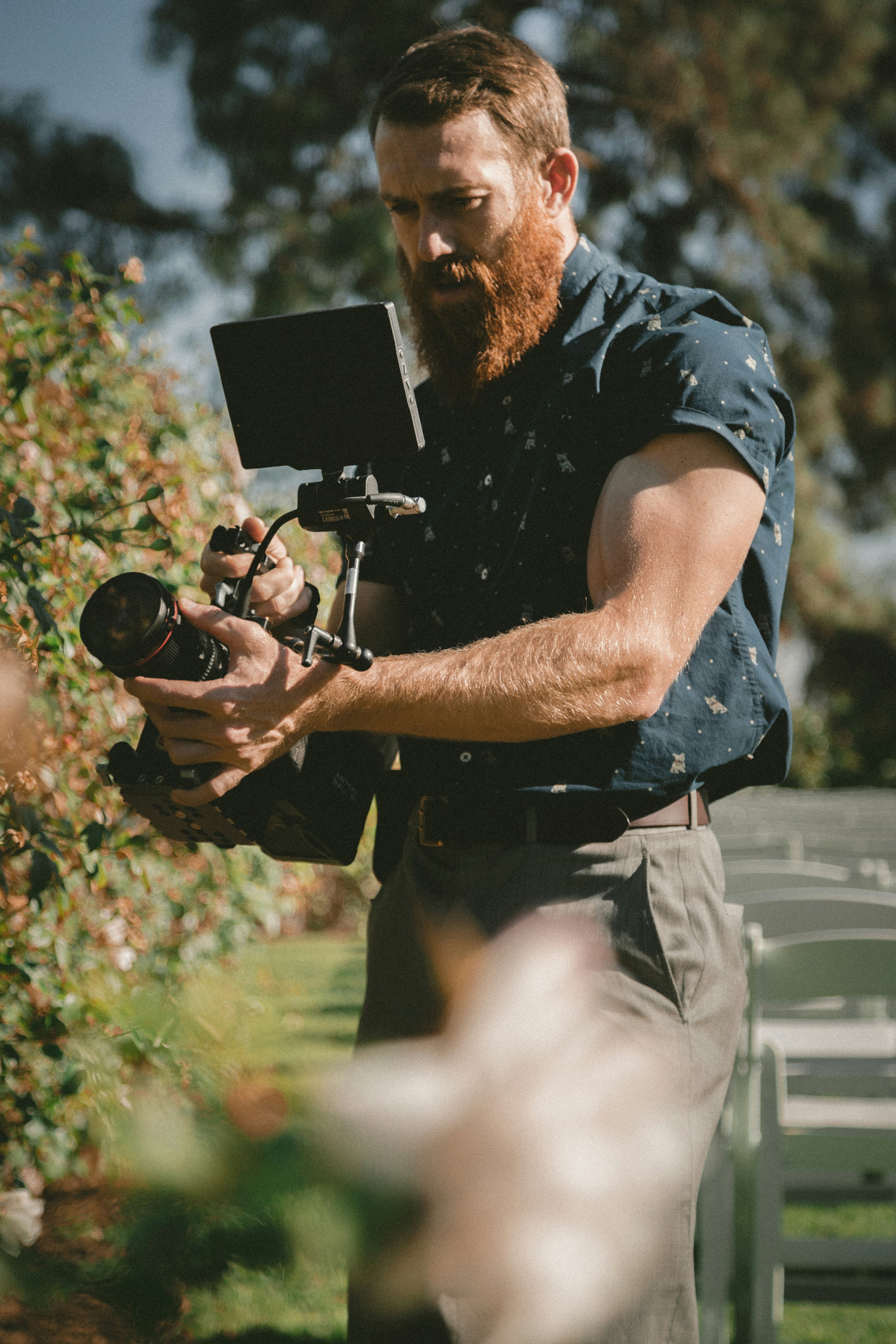 A videographer working with a rigged camera at an outdoor event.